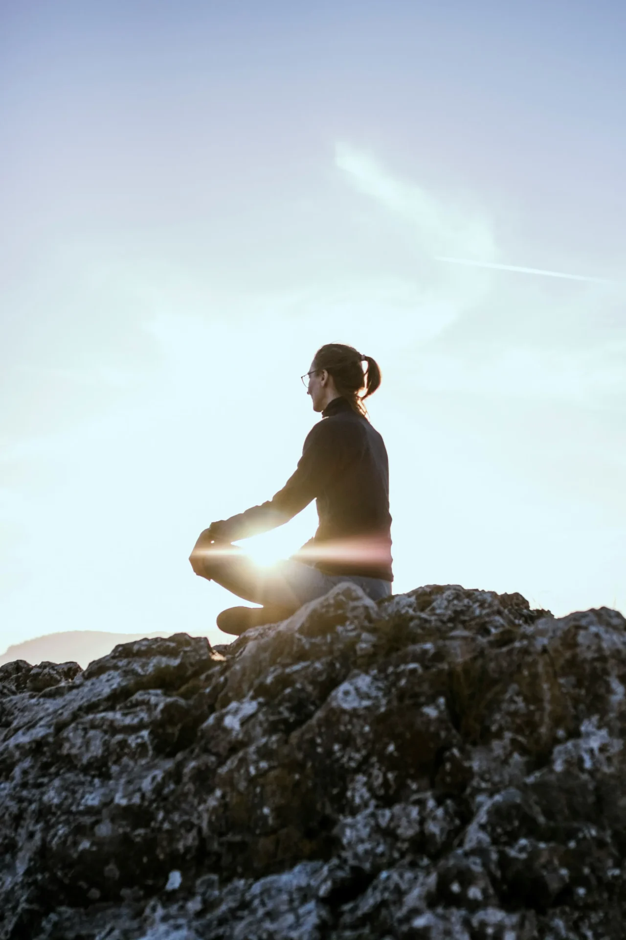 eniko-kis-V58katgrQPY-unsplash Person meditating outdoors beneath a blue sky.